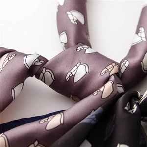 Detailed view of satin silk neck scarves featuring horse head prints and sleek texture