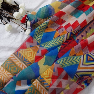 Détail de l'écharpe en coton et lin avec motifs géométriques et pompons rouges