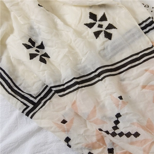Macro shot of cream vintage scarf fabric with geometric star patterns and fringe detail