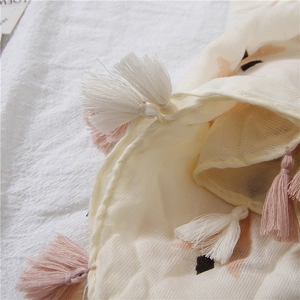 Detailed close-up of light beige linen shawl with soft pink and white tassel edge details