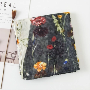 Detail of floral linen scarf with fringe, featuring orange daisy and red carnation prints