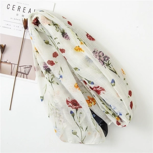 Detail of floral linen-cotton scarf with vibrant flower patterns and tassel accents