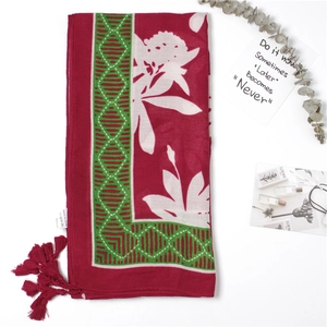 Detail of red floral cotton scarf showing soft leaf print and burgundy corner tassels