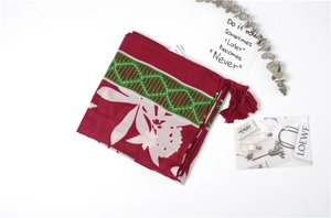 Detail of burgundy and green floral linen scarf with fringes and material tag