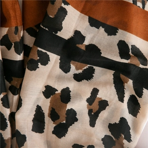 Détail d'une écharpe légère en coton et lin avec imprimé léopard et rayures orange