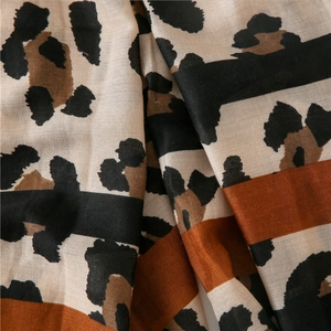Gros plan sur le motif léopard et les rayures orange du foulard en coton et lin tissé