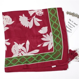 Detail of red beach shawl with white floral patterns, geometric borders and tassels
