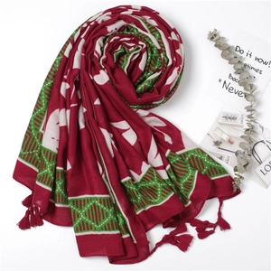 Detail of red and green cotton linen scarf with bohemian leaf patterns and tassels