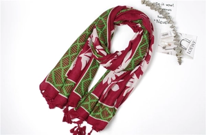 Detailed flat lay of red and green leaf pattern cotton scarf with tassel fringe