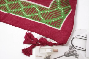Detail of red and green geometric knit scarf featuring long fringe and soft texture