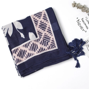 Close-up of navy cotton scarf with white floral patterns and pink tassel detail