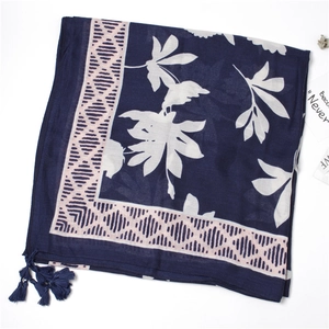 Detail of navy blue cotton linen scarf featuring white leaf prints and decorative tassels