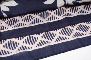 Detail of navy blue linen scarf with white floral print and pink wave striped edges