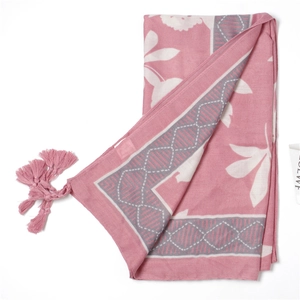 Macro detail of leaf pattern fabric and pink tassels on cotton linen beach scarf