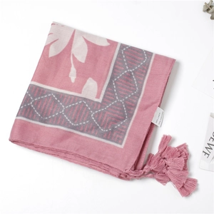 Detail of pink linen blend scarf with white floral patterns and tassel trim edges