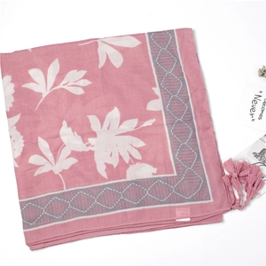 Detail of pink scarf with large white leaf prints, geometric borders and pink tassels