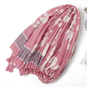 Detailed shot of pink cotton scarf with white floral patterns and tassel edge decoration