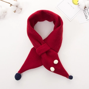 Detail of red knit kids scarf featuring navy pompoms and white circular decorations