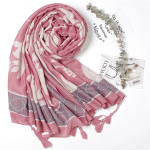 Detail of pink floral cotton scarf featuring decorative tassels and leaf patterns