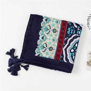Detail of bohemian floral pattern on navy blue linen scarf with decorative tassels