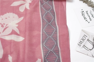 Detail of pink cotton scarf with white floral prints and geometric border patterns