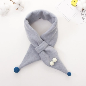 Detailed knit texture of a warm kids scarf featuring white pom-poms and cross-through style