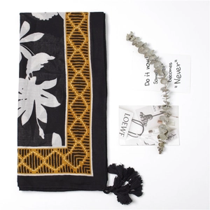 Detail of floral scarf with tropical white flowers, yellow borders and black tassels