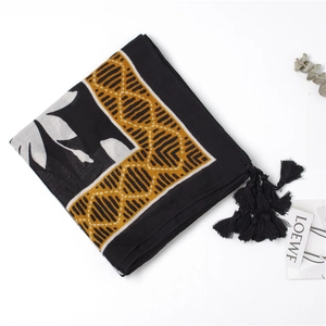 Detail of leaf print cotton linen scarf with geometric borders and black tassel trim