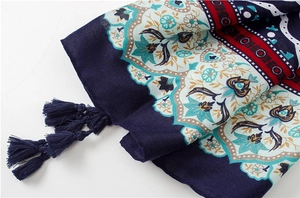 Detail of bohemian floral print scarf with handcrafted navy tassels and soft cotton texture