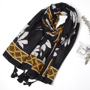 Detail of large leaf print scarf with mustard geometric borders and fringe tassels