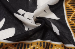 Macro view of cotton linen scarf featuring yellow and black leaf pattern texture