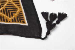 Detail of bohemian black scarf with yellow geometric patterns and handmade black tassels