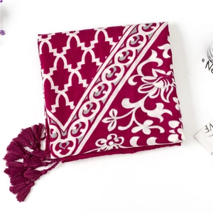 Détail d'une écharpe bohème rouge foncé avec motifs ethniques et bordures à franges
