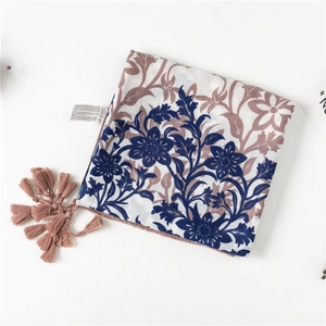 Detailed close-up of floral print cotton scarf with soft pink fringe and care label