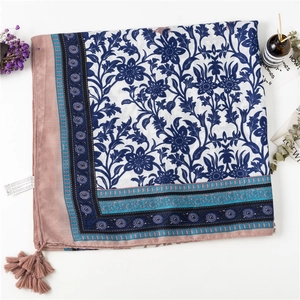 Detail of linen scarf with blue vintage floral patterns and red tassels for beach vacations