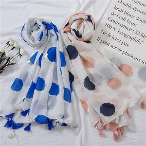 Detailed flat lay of polka dot linen scarves with tassels and white dried flowers decoration