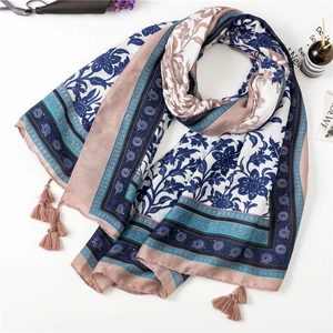 Detail of floral navy blue scarf with geometric textures and pink tassels on white backdrop