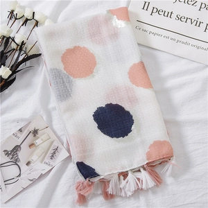 Detail of white cotton linen scarf featuring colorful polka dots and fringe tassels