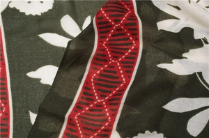 Detail of dark green cotton linen scarf with leaf print and red geometric border