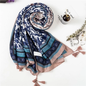 Detail of floral printed linen scarf with blue vine patterns and soft fringe tassels
