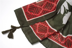 Detail of bohemian scarf with ethnic leaf prints and red fringe tassels on cotton fabric