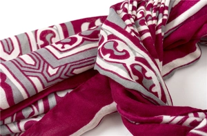 Gros plan sur les motifs géométriques exotiques magenta et gris de l'écharpe tissée