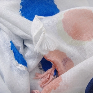 Detail of white cotton linen scarf with blue and pink polka dots and fringe tassels