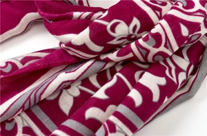 Gros plan détaillé d'une écharpe bohème rouge foncé aux motifs floraux et texture tissée