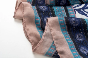 Detail shot of bohemian floral linen silk scarf with intricate rolled hem and vibrant patterns