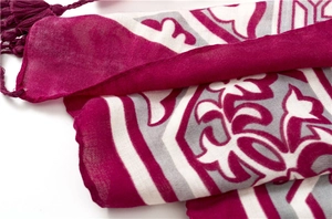 Gros plan du motif tribal bohème et des franges sur l'écharpe légère magenta