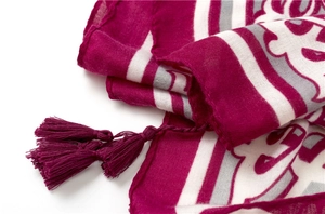 Gros plan d'une écharpe bohème magenta avec motifs tissés et détails de pompons