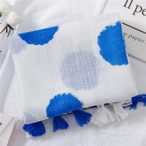 Detailed view of white cotton linen scarf with navy blue polka dots and long tassels