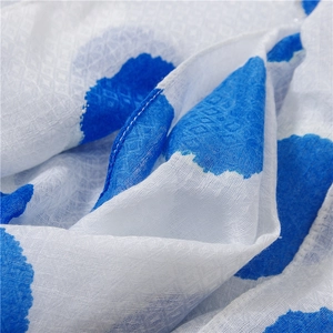 Macro detail of breathable cotton-linen scarf with blue polka dots and diamond texture