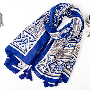 Mise à plat d'écharpe bohème avec motifs géométriques et pompons bleus sur fond blanc